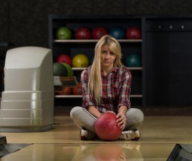Woman holding a bowling ball sitting on the floor Stock Photo 01
