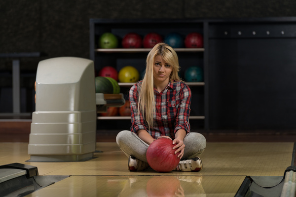 Woman holding a bowling ball sitting on the floor Stock Photo 01