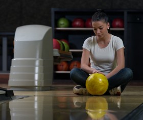 Woman holding a bowling ball sitting on the floor Stock Photo 02