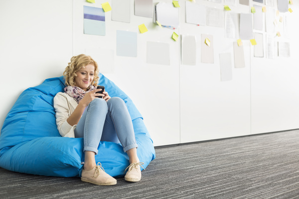 Woman playing smart phone while sitting in inflatable chair Stock Photo