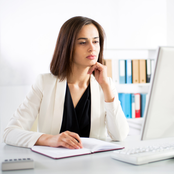 Woman sitting at computer and recording information Stock Photo