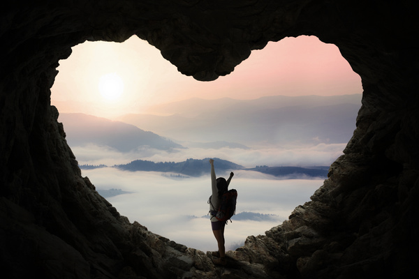 Woman standing in heart shaped cave mouth Stock Photo