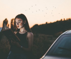 Young woman reading book at dusk Stock Photo