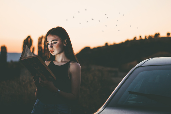 Young woman reading book at dusk Stock Photo