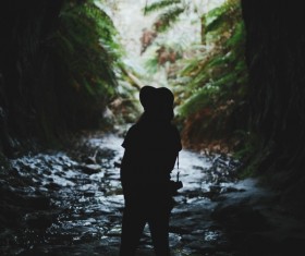woman exploring dark mountain cave Stock Photo