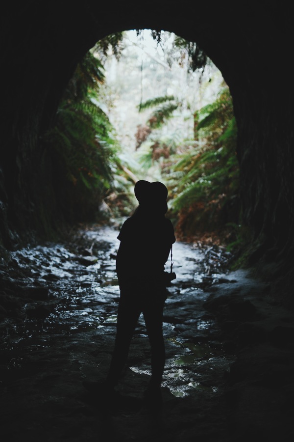 woman exploring dark mountain cave Stock Photo