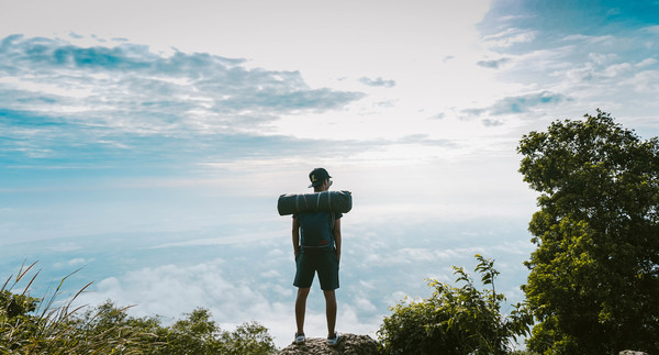 Backpacker standing on top of mountain enjoys high altitude scenery Stock Photo