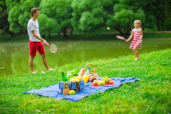Father and daughter playing tennis and picnic food Stock Photo