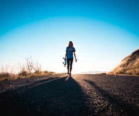 Lonely woman walking on empty road Stock Photo