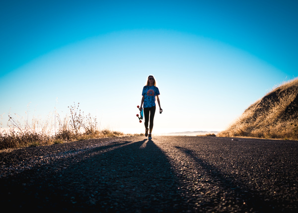 Lonely woman walking on empty road Stock Photo