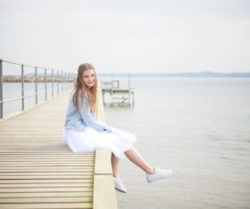 Maiden sitting on wooden bridge Stock Photo