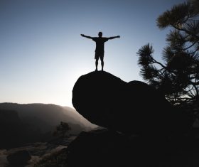 Man posing on big stone at dusk Stock Photo