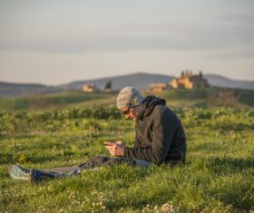 Man sitting on grass playing with cell phone Stock Photo
