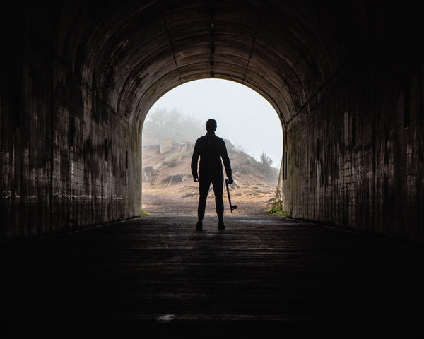 Man standing alone in dark tunnel Stock Photo