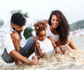 Parents playing with daughter on the beach Stock Photo