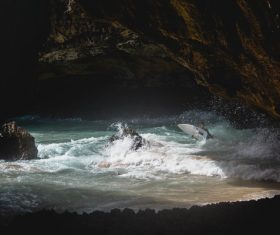 Person joyful with splashing wavy beach in cave Stock Photo
