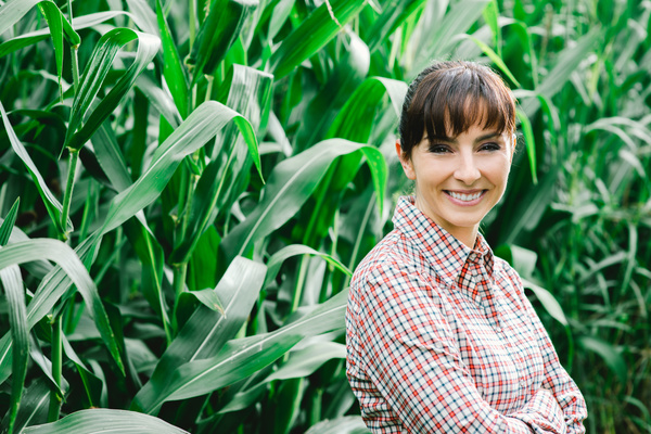Smiling woman standing in corn field Stock Photo