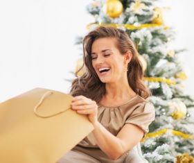 Smiling young woman with shopping bags near christmas tree 01