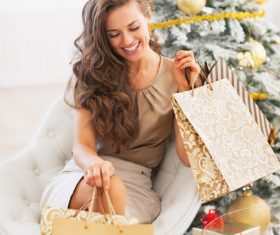 Smiling young woman with shopping bags near christmas tree 04