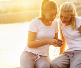 Two girls using smartphones listening to music Stock Photo 01
