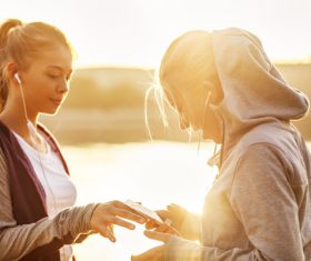 Two girls using smartphones listening to music Stock Photo 03