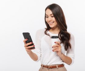 Woman holding coffee looks at mobile phone information Stock Photo