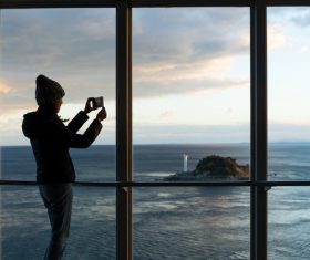 Woman photographing seascape with smartphone Stock Photo