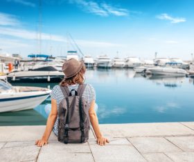 Woman sitting on pier watching yacht Stock Photo