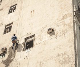 Worker climbing on building wall with rope Stock Photo