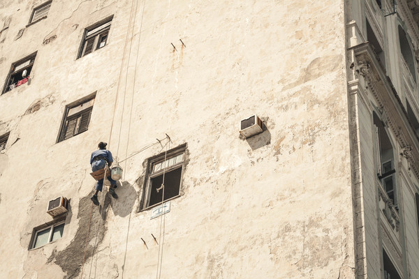 Worker climbing on building wall with rope Stock Photo