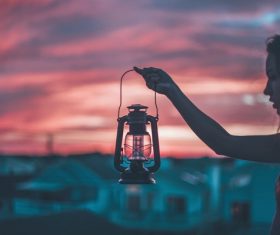 Young girl holding classical lamp at dusk Stock Photo