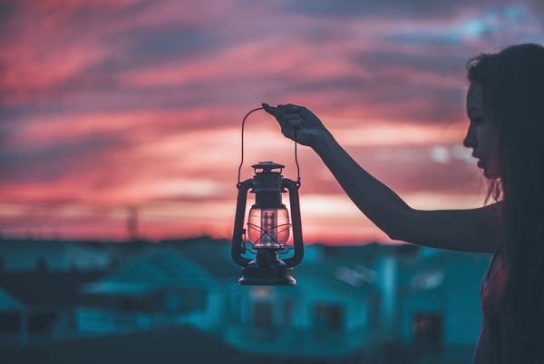Young girl holding classical lamp at dusk Stock Photo