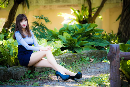 Asian pretty girl sitting on flower bed posing Stock Photo