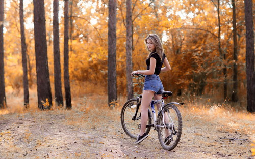 Beautiful girl riding bicycle looks back Stock Photo