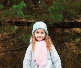 Beautiful little girl in front of pine trees Stock Photo