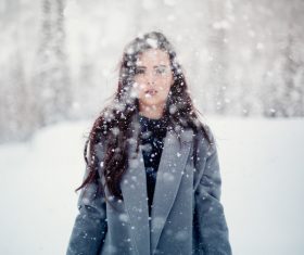 Beautiful young woman posing in falling snow Stock Photo