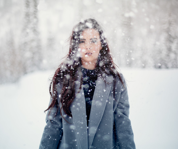 Beautiful young woman posing in falling snow Stock Photo