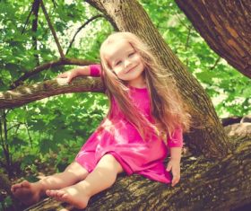 Blond little girl on big tree Stock Photo