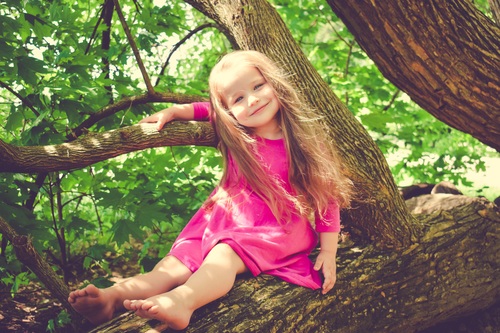 Blond little girl on big tree Stock Photo