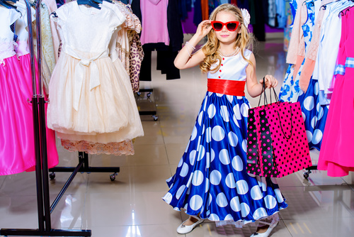 Cute little girl holding shopping bags posing in mall Stock Photo
