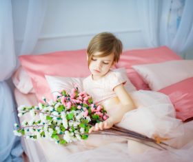 Dressed up beautiful little girl holding bouquet sitting on bed Stock Photo 03