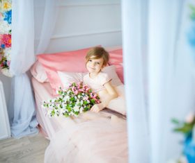 Dressed up beautiful little girl holding bouquet sitting on bed Stock Photo 04