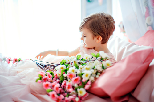 Dressed up beautiful little girl holding bouquet sitting on bed Stock Photo 05