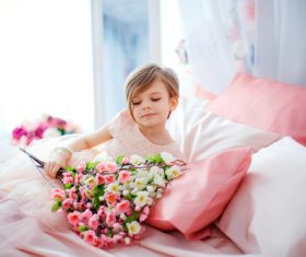 Dressed up beautiful little girl holding bouquet sitting on bed Stock Photo 06