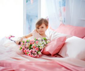 Dressed up beautiful little girl holding bouquet sitting on bed Stock Photo 07