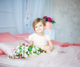 Dressed up beautiful little girl sitting on the bed Stock Photo 01
