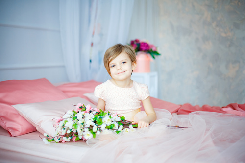 Dressed up beautiful little girl sitting on the bed Stock Photo 01