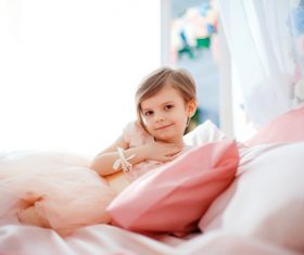 Dressed up beautiful little girl sitting on the bed Stock Photo 02