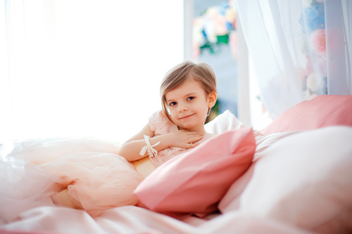 Dressed up beautiful little girl sitting on the bed Stock Photo 02
