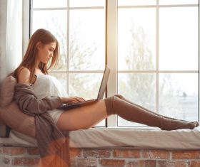 Girl sitting on the windowsill using laptop Stock Photo